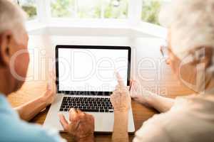 Rear view of senior couple using laptop