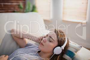 Pretty woman lying on the couch listening music