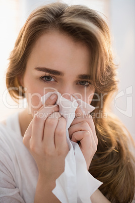 Woman blowing her nose on couch