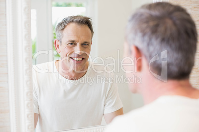 Handsome man looking at himself in the mirror