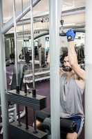 Focused man using weights machine for arms