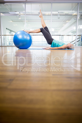 Fit blonde on mat exercising with fitness ball