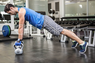 Muscular man doing push ups with kettlebells