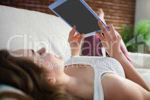 Pretty woman lying on the couch while using tablet