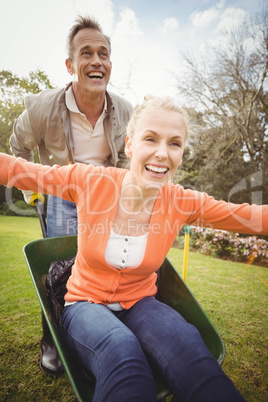 Husband pushing wife in a wheelbarrow