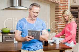 Husband using tablet while wife having breakfast
