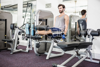 Focused man using weights machine for legs