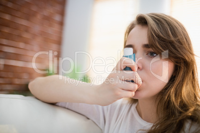 Woman using her inhaler on couch