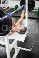 Muscular man lifting barbell on bench