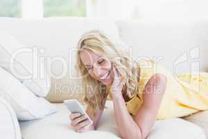 Happy woman using smartphone on the sofa