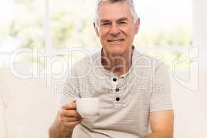 Smiling senior man holding mug