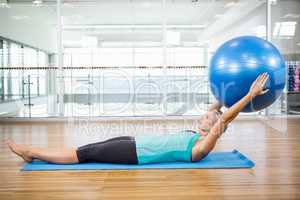 Fit blonde on mat holding fitness ball