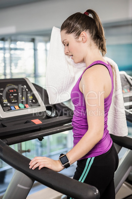 Tired woman on treadmill wiping sweat with towel