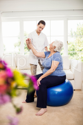 Physiotherapist taking care of sick elderly patient
