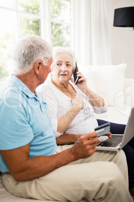 Smiling senior couple using laptop and smartphone