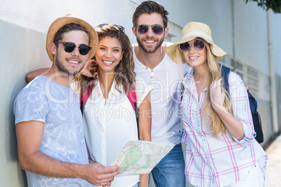 Hip friends holding map and smiling at the camera