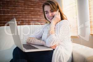 Pretty woman calling on the phone while watching her laptop