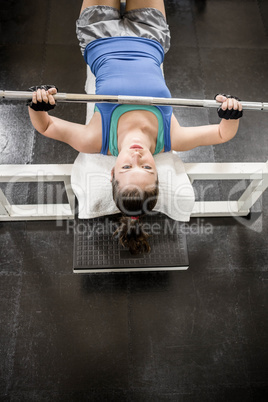 Fit woman lifting the barbell on bench