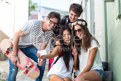 Hip friends taking selfie sitting on steps