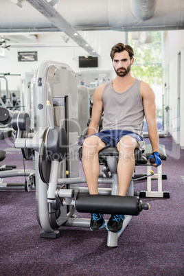 Focused man using weights machine for legs