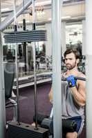 Focused man using weights machine for arms