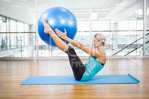 Fit blonde on mat holding fitness ball