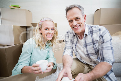 Smiling couple packing mug in a box