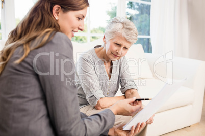 Smiling businesswoman showing documents to senior woman