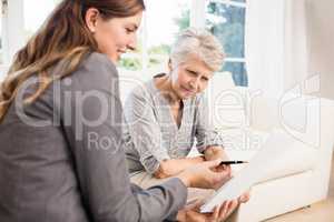 Smiling businesswoman showing documents to senior woman