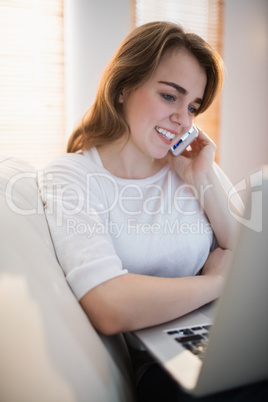 Pretty woman calling on the phone while watching her laptop