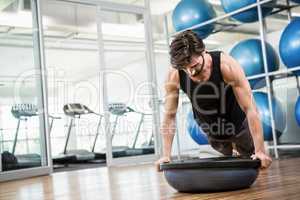 Serious man doing exercise with bosu ball