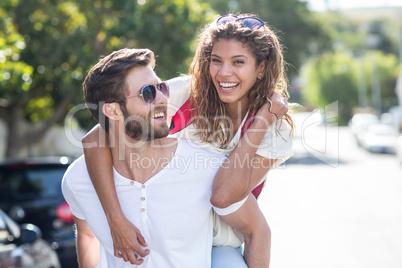 Hip man giving piggy back to his girlfriend