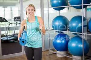 Fit blonde holding mat and showing thumb up