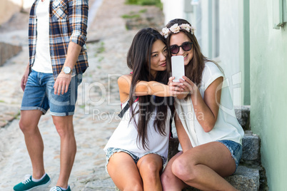 Hip friends taking selfie sitting on steps