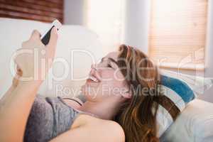 Pretty woman lying on the couch using phone