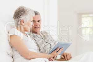 Senior couple using tablet on bed