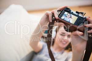 Pretty woman lying on the couch taking selfie while listening mu