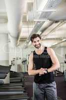 Smiling man on treadmill looking at smartwatch