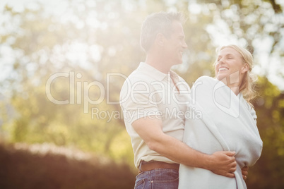 Husband hugging his wife in a blanket