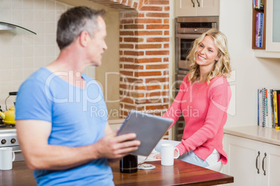 Happy husband using tablet while wife having breakfast