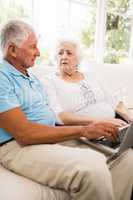 Focused senior couple using laptop