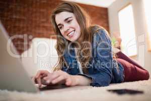 Pretty woman lying on the couch using laptop