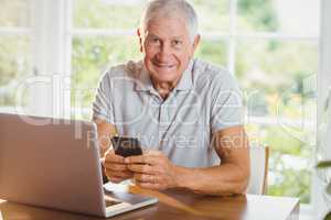 Senior man using his laptop and smartphone