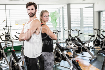 Fit couple standing back to back with arms crossed