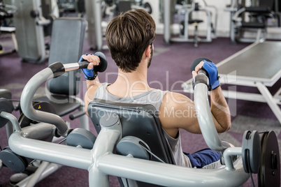 Focused man using weights machine for arms