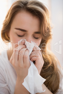 Woman blowing her nose on couch