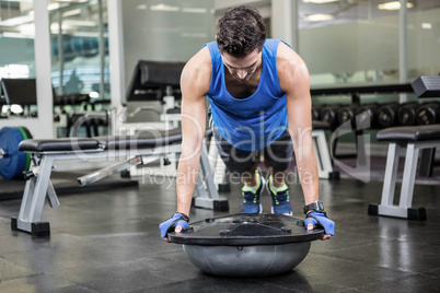 Muscular man doing push up with bosu ball