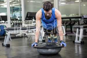 Muscular man doing push up with bosu ball