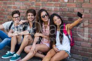 Hip friends sitting on the floor and taking selfie