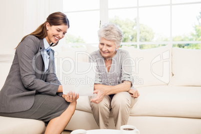 Smiling businesswoman showing documents to senior woman